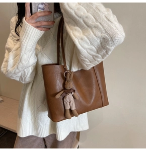 Detail of dark brown leather tote bag with cute knit rabbit charm on shoulder strap