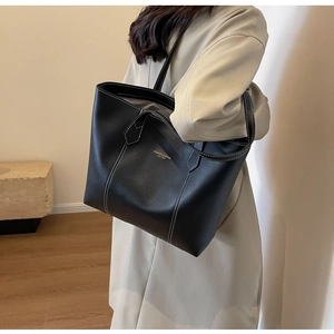 Detail of black leather tote bag featuring contrast white stitching and gold branding