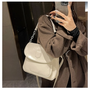 Detail of cream white shoulder bag featuring glossy PU leather and silver chain strap