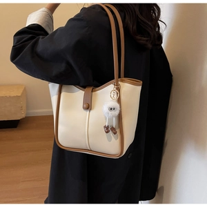 Dettaglio della borsa tote grande crema con spalline marroni e ciondolo di peluche