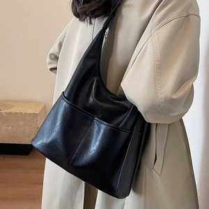 Borsa a secchiello hobo in pelle nera abbinata a un trench beige per un look autunnale retrò