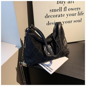 Détail du sac cabas matelassé noir avec logo métallique rond et bandoulière en chaîne chic