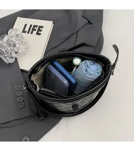 Spacious interior of black quilted bucket bag holding a phone, umbrella and cosmetics