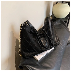 Détail du sac hobo matelassé noir avec chaîne dorée et emblème de logo embossé