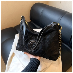 Détail du sac cabas matelassé noir avec chaîne dorée et logo métallique circulaire M