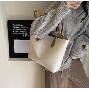 Detail of minimalist cream tote bag with brown straps styled with an autumn sweater