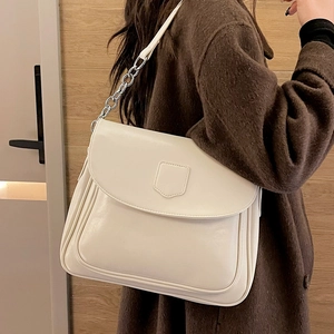 Minimalist cream white leather hobo bag with silver chain strap on wool coat