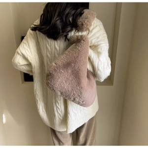 Plush brown shoulder bag with metallic ring handle shown on model in home setting