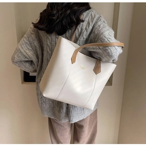 Detail view of off-white leather tote bag with brown straps on a model's shoulder