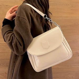 Cream leather shoulder bag with chain strap shown on a wool coat for a vintage look