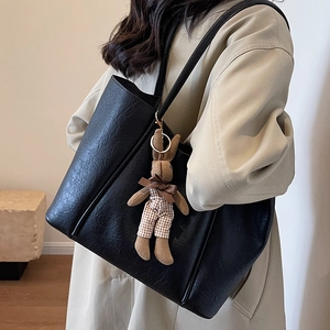 Classic black embossed leather tote bag with a cute plush rabbit charm for daily commuting