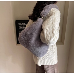 Close-up of purple faux fur tote bag with gold metal ring buckle on soft knit sweater
