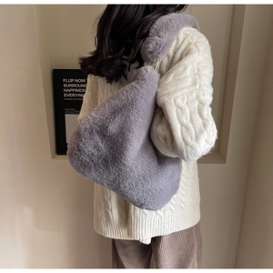 Detail of gray faux fur shoulder bag with metal ring handle on winter outfit