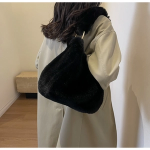 Detail of black faux fur shoulder bag with gold metal rings and spacious interior design