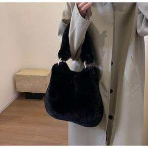 Detail of black faux fur tote bag with gold metal rings and fluffy winter texture