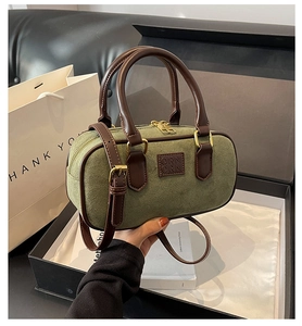 Dettaglio della borsa Boston in camoscio verde con manici in pelle e logo ORN a sbalzo
