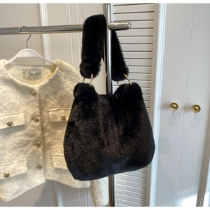 Detail of black faux fur handbag with elegant gold ring hardware on a metal hanger