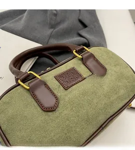 Dettaglio borsa a mano in pelle scamosciata verde con manici in pelle e oro