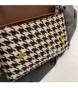 Detail of magnetic buckle closure on houndstooth tote bag with brown leather flap