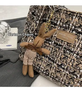 Close-up of a brown knitted rabbit charm with bow on a tweed tote bag accessory