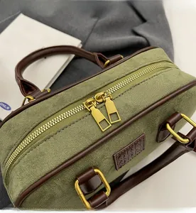 Dettaglio borsa Boston in camoscio verde avocado con doppia cerniera e bordi in pelle