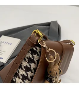 Close-up of brown leather and houndstooth tote with gold hardware and rabbit charm