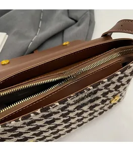 Close-up of golden zipper detail and houndstooth texture on leather tote bag
