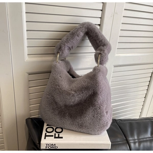 Close-up of plush faux fur handbag featuring large gold metal rings on the handles