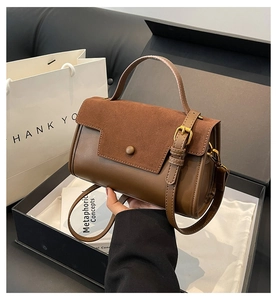Detail of a dark brown patchwork handbag featuring smooth leather and suede textures