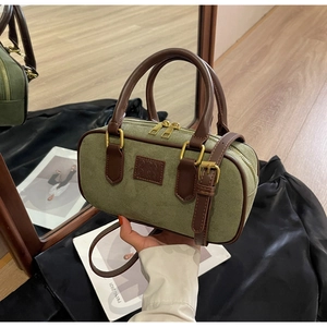 Dettaglio borsa boston in camoscio verde con manici in pelle e finiture in metallo dorato