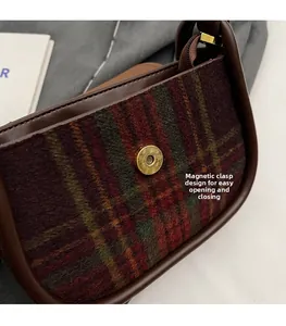 Close-up of magnetic snap closure on vintage red and green plaid wool saddle bag