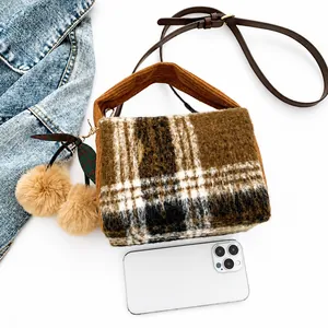 Petit sac Boston à carreaux marron montré à côté d'un smartphone pour comparer la taille
