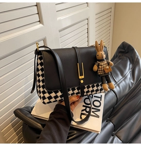 Detail of checkered fabric tote bag with elegant gold metal buckle and cute bunny pendant