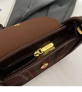 Macro shot of premium gold zipper hardware with engraved logo on brown leather saddle bag