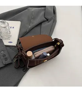 Detail view of plaid saddle bag interior capacity with leather trim and flap closure
