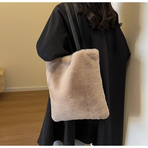 Détail d'un sac cabas en peluche avec bandoulière en cuir noir porté sur l'épaule