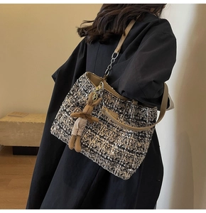 Detail of tweed tote bag with woven texture, metal chain strap and cute rabbit pendant