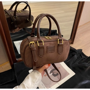 Dettaglio borsa Boston in camoscio marrone con finiture dorate e manici in pelle