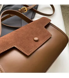 Detail of brown leather and suede shoulder bag with geometric flap and gold buckle