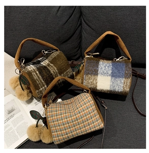 Close-up of three plaid Boston bags in wool material with cherry charms and shoulder straps