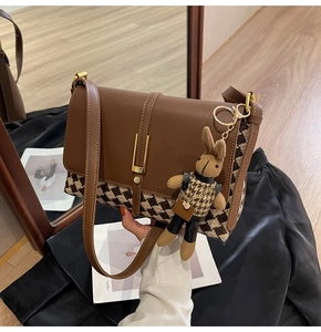 Detail of brown leather tote bag with houndstooth fabric and cute rabbit charm