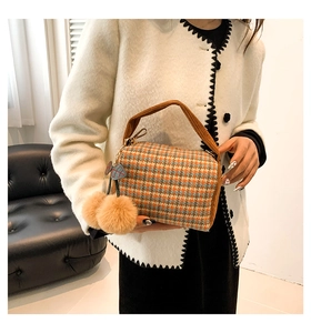 Close-up of a mini Boston bag with orange houndstooth pattern and brown corduroy handle