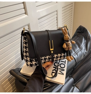 Detail of houndstooth crossbody bag featuring gold U-shaped buckle and brown plush bunny charm