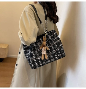 Close-up of black and white tweed tote bag with leather straps and a cute bunny pendant