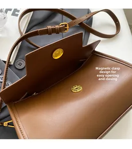 Close-up of brown leather bag featuring a gold magnetic buckle and adjustable strap