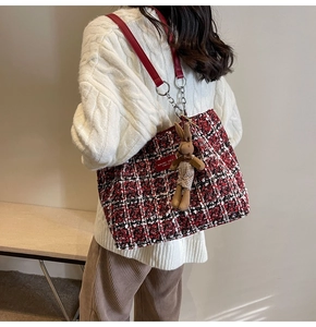 Detail of red tweed tote bag featuring checkered weave and cute rabbit charm on model