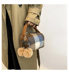 Detail view of plaid wool Boston bag with decorative cherry pom-poms and velvet handles