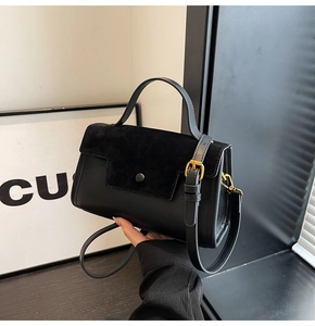 Detail of black crossbody bag featuring smooth leather and suede patchwork with gold buckle