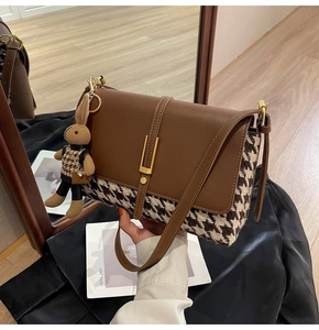 Detail of vintage houndstooth tote bag with brown leather accents and a rabbit charm