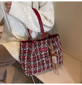 Detail of red and black tweed tote bag with leather handles and plush rabbit charm